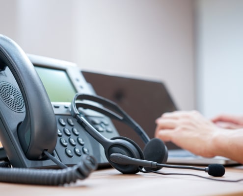 headset-with-blurred-call-center-employee-hand-working-operation-room